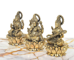 Close side view of brass Lakshmi, Ganesha and Saraswati idols on lotus plinths