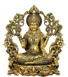 Lakshmi Maa brass idol close-up, ornate floral arch, seated pose with raised hands