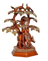 Dreiviertelansicht: Krishna auf Sockel, Flöte, Baum mit Blättern und zwei Vögeln