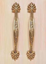 Brass main door handle pair on light wood, vertical leaf engraving with top and bottom rosettes.