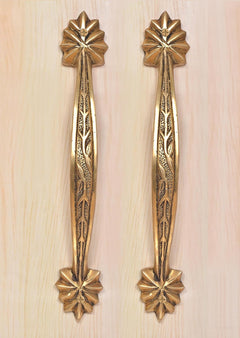 Brass main door handle pair on light wood, vertical leaf engraving with top and bottom rosettes.
