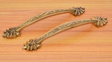 Carved leaf brass door handles with rounded backplate and floral rosette details, pair.