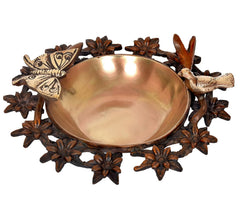 Brass urli bowl with dark floral ring and bird-and-butterfly motifs around the edge