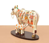 Side view of resin Kamdhenu cow with calf figure, white body and colorful people patterns
