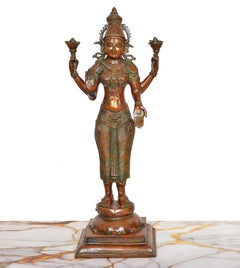 Standing brass Lakshmi murti facing front, four hands holding lotuses, detailed jewelry