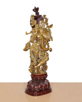 Radha Krishna brass idol, gold figure with raised hand and maroon headgear on red pedestal