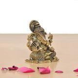 Brass Lord Ganesha idol in profile, seated with raised hands and textured patterned base