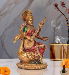 Saraswati idol on swan, veena in raised hand; golden details with red and green clothing