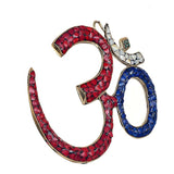OM wall hanging sculpture with red and blue mosaic segments and small charm accents