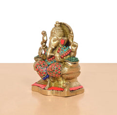 Brass Ganesha figurine side view, multicolor necklaces, red patterned pants, golden base