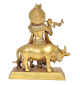 Back view of brass Krishna statue with flute on cow, detailed carvings, ornate platform