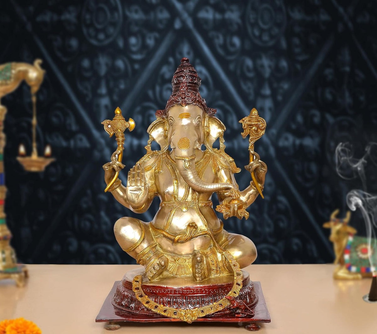 Brass Ganpati Bappa idol with gold body, red crown, four arms, on decorated base