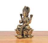 Side view of brass Lakshmi idol on lotus base with beaded garland and ornaments