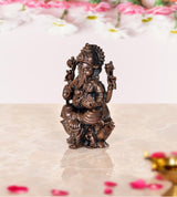 Copper Ganesha idol statue, side view of seated figure with ornate headdress and arms