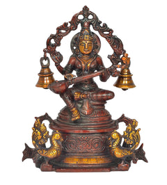 Saraswati brass idol on swan with veena, ornate arch, and gold-tone bell stands