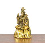Golden brass seated goddess statue holding staff, detailed jewelry and crown