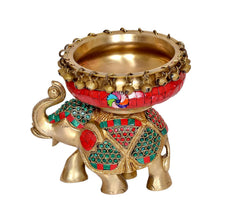 Brass elephant statue with red urli bowl, teal and green patterned body decor