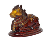 Close-up of seated Nandi bull statue face and saddle ornaments, gold and dark brown