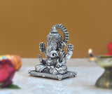 Seated Ganpati idol in brass finish, detailed jewelry and crown, front view.