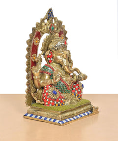 Brass Ganpati idol holding staff, multicolour patterned outfit with golden base