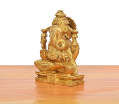 Brass Ganpati murti close-up side view, ornate face and crown, golden finish