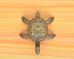 Brass tortoise figurine, top view with star-like engravings and raised head