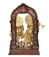 Back view of brass Radha Krishna idol statue in dark arch frame with base