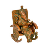 Brass Ganesha statue, angled view, reading book on carved chair seat