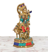 Front 3/4 view: brass Krishna playing flute idol with cow figure, colorful enamel details