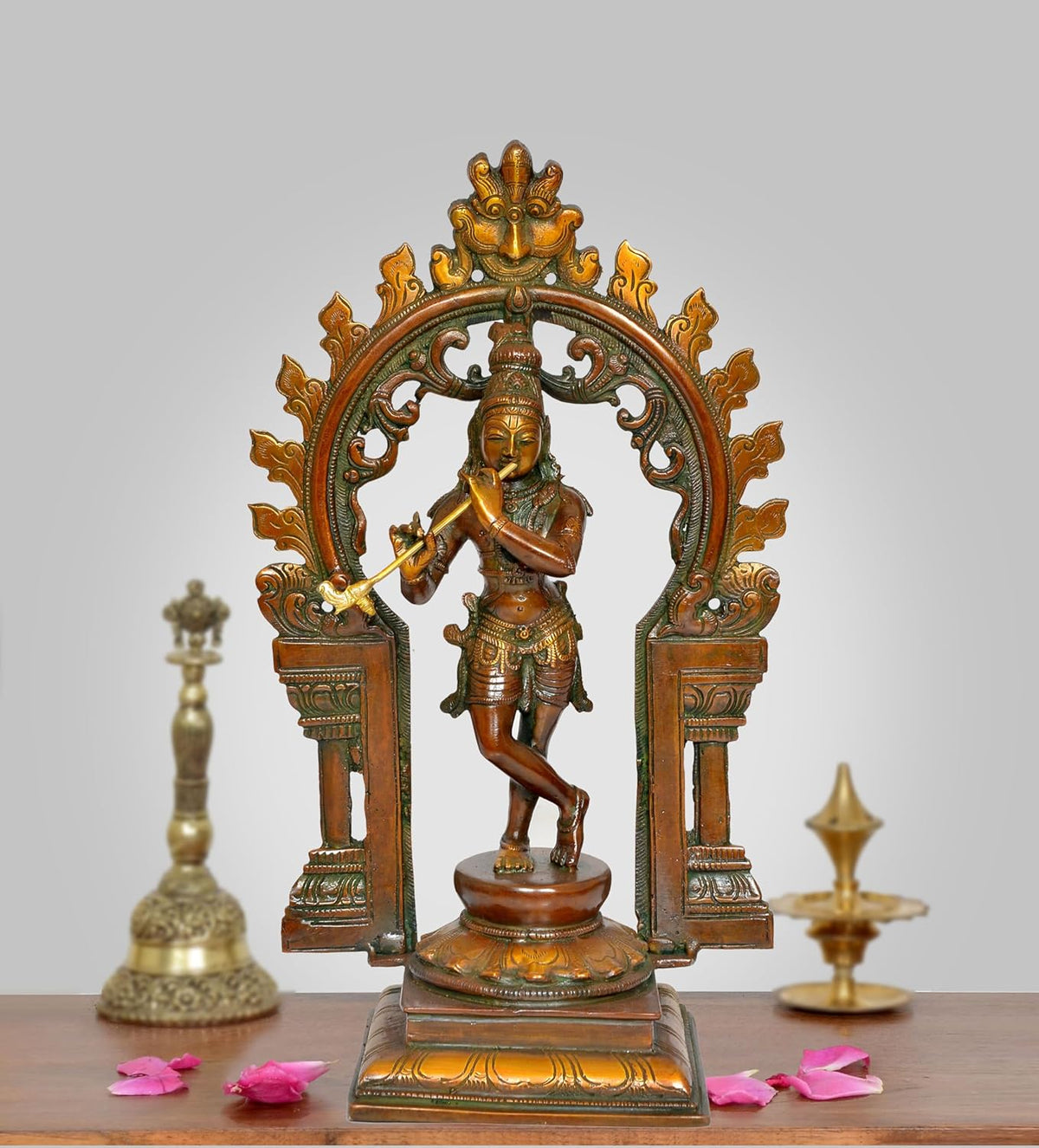 Brass Krishna idol playing flute in ornate Kirtimukha frame sculpture, 13 in height