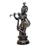 Brass Krishna statue holding flute, ornate crown, dark pedestal base