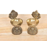 Close view of brass diya shankh oil lamp stands showing textured bowls and bases
