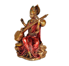 Resin Mata Saraswati idol in side view, veena across arms, red sari folds, gold drum
