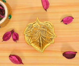 Golden metal oil diya lamp, embossed bird motif on leaf-like holder; height 1 inch