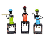 Three iron musician figurines on dark wooden block bases, facing forward with instruments