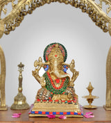 Ganesha idol in gold tone with multicolour jewels, seated on ornate striped base