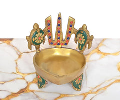 Brass diya oil lamp with open bowl, teal side emblems, and chakra on the backrest