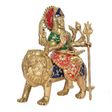 Durga Maa brass statue on lion, green top and red patterned skirt, holding staff