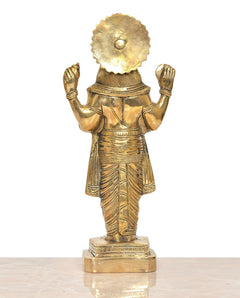Brass deity statue from behind with circular halo-like ornament and raised arms