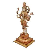 Brass Shiva statue side view, four arms holding trident, gold-red ornamental accents