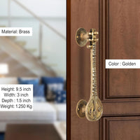 Golden brass sitar-shaped door handle pair mounted on a wooden door