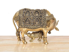 Brass cow and calf showpiece, full-body view, ornate square deity motifs on saddle