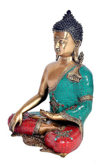 Brass Buddha sitting pose, side view with turquoise cloth and red patterned cushion