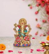 Gold-toned Ganesha idol statue with red and turquoise jeweled detailing, on base