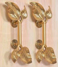 Golden brass twin-leaf door handles with decorative leaves and rosette bases