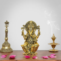 Golden brass Ganesh statue with raised hands, seated on lotus