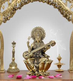 Brass Maa Saraswati statue seated on lotus, holding veena, ornate crown and jewelry