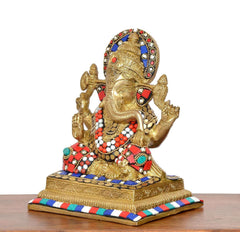 Brass Ganesha idol side view, multicolour jewels on crown and red-blue-white garlands
