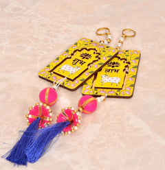 Close-up of two Shubh Labh door hangings: yellow tags with cow motifs and tassels