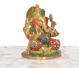 Close three-quarter view: brass Ganesha with red cloth, turquoise round inlays, detailed hands